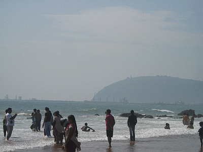 People bathing at Ramkrishna Beach with the 'Dolphin's Nose' in the background